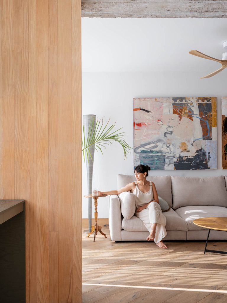 Mujer descansando en el salón de una vivienda reformada con estilo minimalista